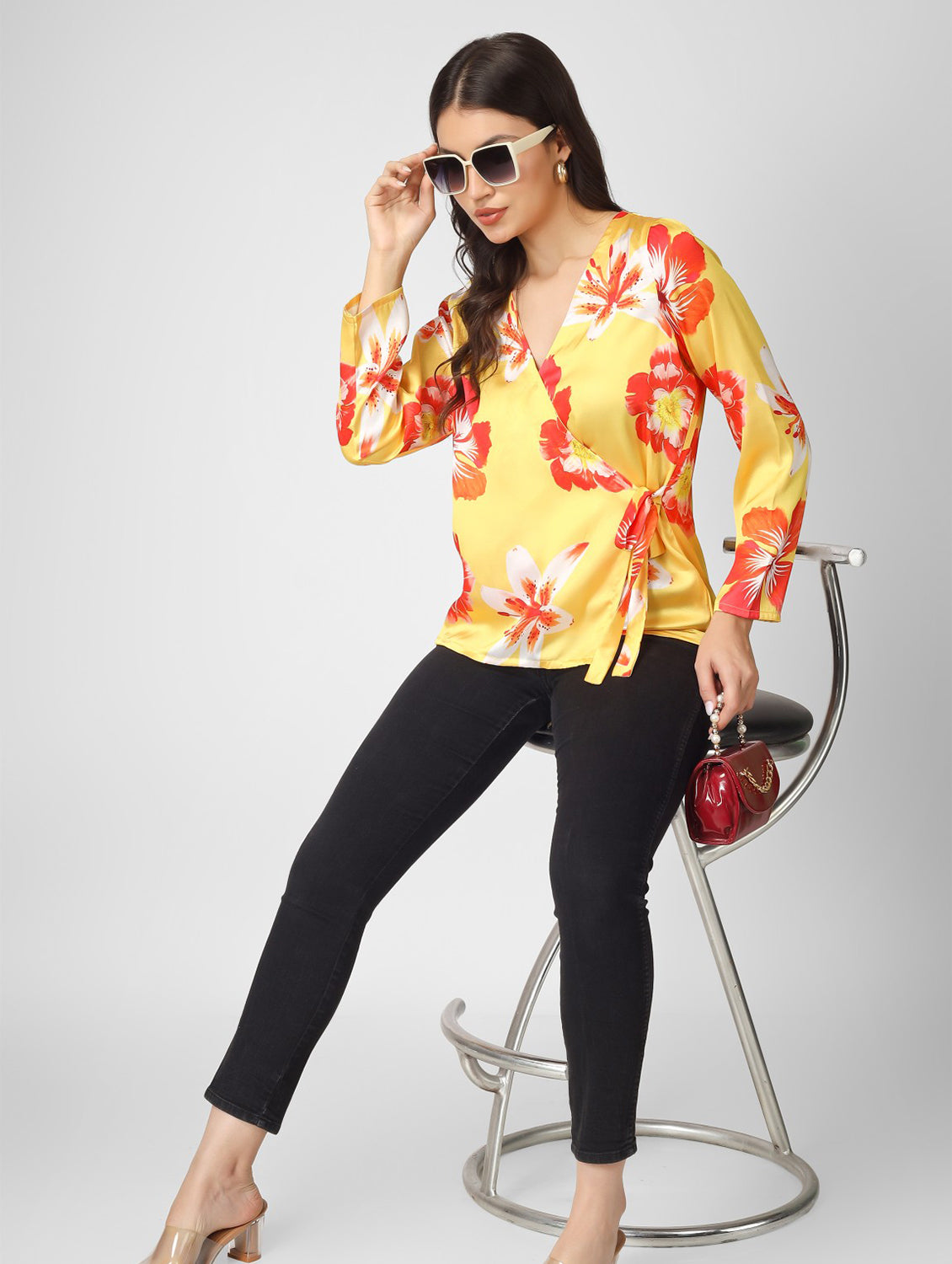 Bright and stylish, this printed yellow satin top features a chic overlap design with full sleeves and a trendy tie-knot detail.